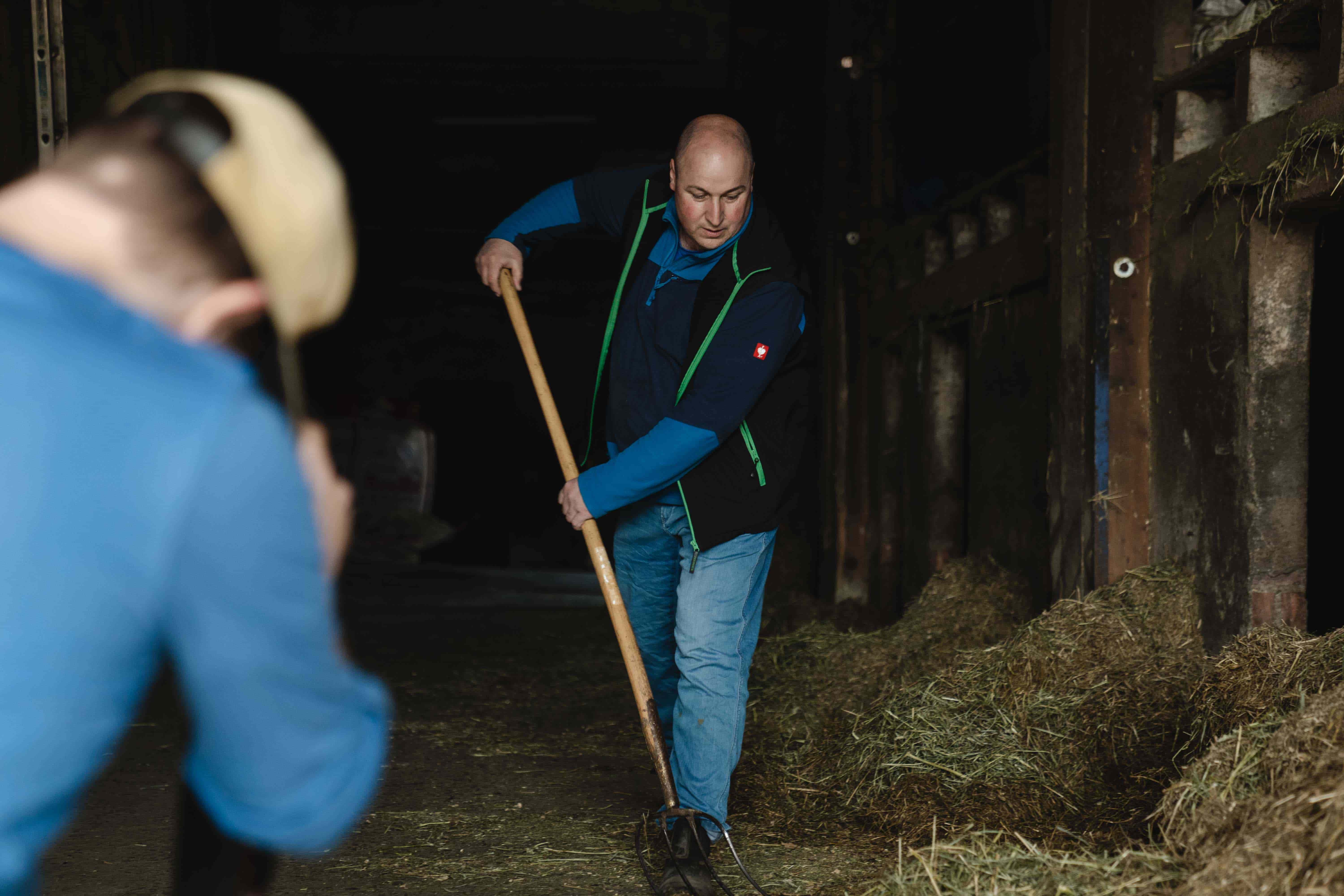 Un fermier balaye l'étable et est filmé en train de le faire.