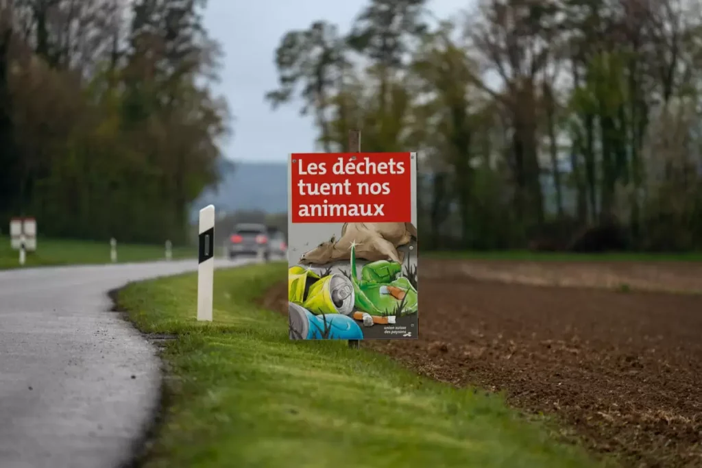 Un panneau portant l'inscription « Les déchets tuent nos animaux » au bord d'une route.