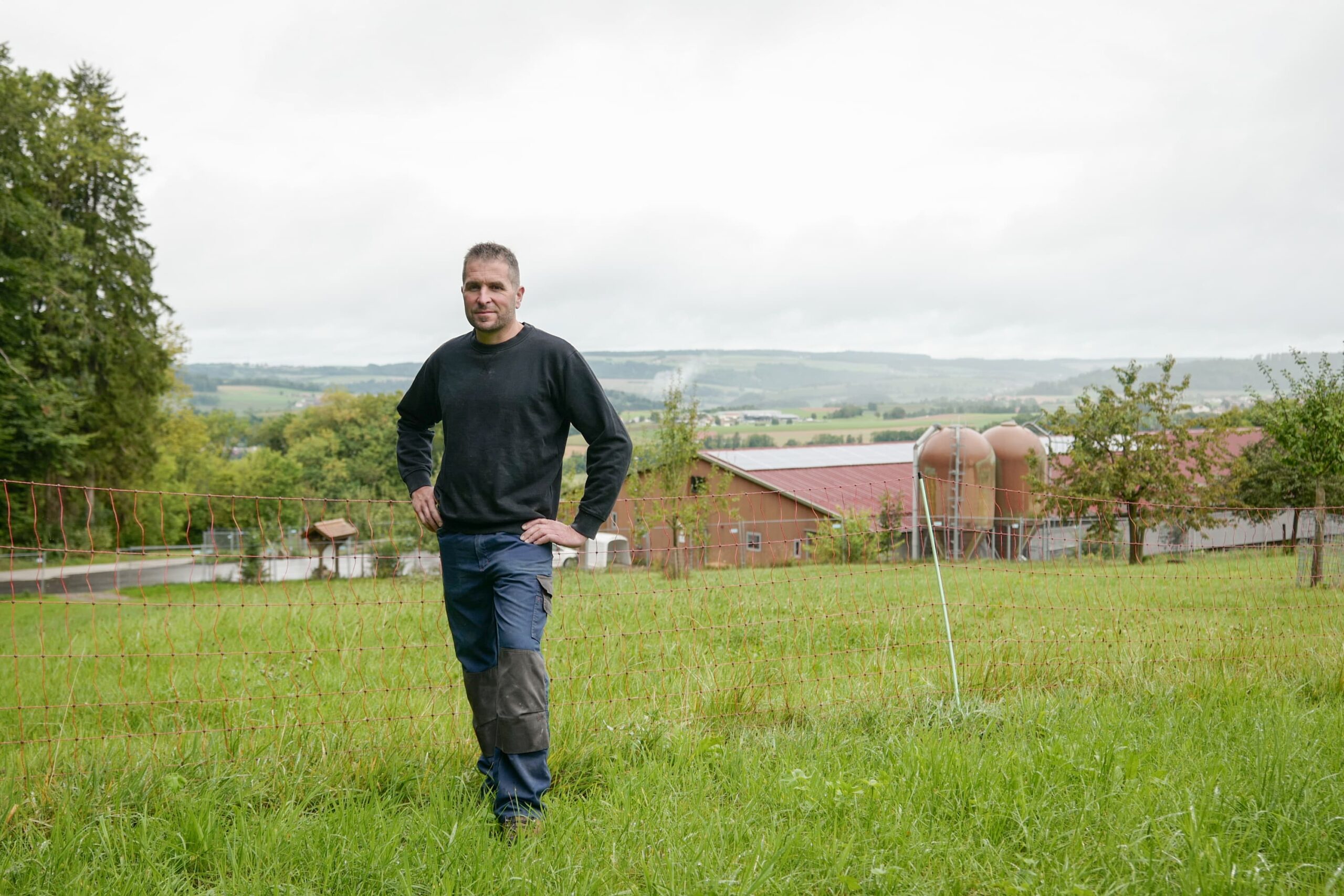 Un paysan se tient debout dans un pré.